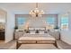 Serene main bedroom with a stylish chandelier, neutral decor, and large windows for natural light at 15791 W Kendall St, Goodyear, AZ 85338