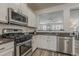 Modern kitchen featuring stainless steel appliances, granite countertops, and an open layout to living area at 19323 E Canary Way, Queen Creek, AZ 85142