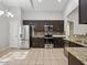 Open kitchen with stainless steel appliances, granite countertops, dark cabinetry, and tile flooring at 21533 N Greenway Rd, Maricopa, AZ 85138
