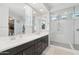 Modern bathroom with double vanity, stylish mirrors, and glass-enclosed shower featuring white subway tile at 22023 N 28Th Pl, Phoenix, AZ 85050