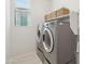 Bright laundry room with side-by-side washer and dryer and storage shelves with wicker baskets at 22023 N 28Th Pl, Phoenix, AZ 85050