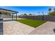 Wide backyard featuring a large, turfed area, a paved patio, and a covered seating area, all surrounded by a high brick wall at 2926 E Corrine Dr, Phoenix, AZ 85032