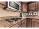 This kitchen features granite counters, a gas cooktop, stainless steel appliances, and dark wood cabinets at 29506 N 21St Ave, Phoenix, AZ 85085