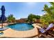 Relaxing backyard pool featuring mature landscape, rock accents, and an umbrella covered lounge at 29506 N 21St Ave, Phoenix, AZ 85085