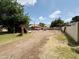 Backyard view with a dirt lot surrounded by a fence, trees, and other properties in the area at 3215 W Orangewood Ave, Phoenix, AZ 85051