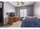 Bedroom with blue bedding, carpet, a ceiling fan, window, and a desk underneath a television at 4243 E Jasper Dr, Gilbert, AZ 85296
