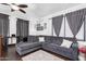 Comfortable living room with dark gray L-shaped couch, dark wood floors and ceiling fan at 4243 E Jasper Dr, Gilbert, AZ 85296