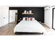 Comfortable bedroom with black accent wall, decorative shelves, modern furnishings, and light colored wood floors at 4317 E Ludlow Dr, Phoenix, AZ 85032