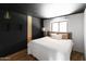 Modern bedroom with a black accent wall, stylish lighting, and a comfortable bed with decorative pillows at 4317 E Ludlow Dr, Phoenix, AZ 85032