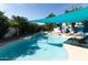 Sunlit swimming pool with blue shade covering and landscaping that offer a comfortable recreational space at 4317 E Ludlow Dr, Phoenix, AZ 85032