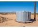 A large, above-ground water tank is situated on a desert lot, near to a utility pole at 54073 W Stallion Rd, Maricopa, AZ 85139