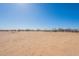 An empty landscape with some desert plants under a blue sky, showcasing the property's potential at 54073 W Stallion Rd, Maricopa, AZ 85139
