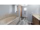 Bathroom featuring a bathtub with stone surround and wood look floors and a storage cabinet at 633 Leisure World --, Mesa, AZ 85206