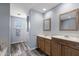 Bathroom featuring dual sinks with wood cabinets, a decorative mirror, and a glass block window at 633 Leisure World --, Mesa, AZ 85206