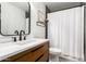 Well-lit bathroom showcases a vanity, dark fixtures, mirror, shelving and shower with curtain at 6869 E Flossmoor Ave, Mesa, AZ 85208