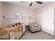 Sweet Bedroom features a crib, soft chair, ceiling fan, and playful decorative accents at 6869 E Flossmoor Ave, Mesa, AZ 85208