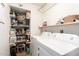 Bright laundry room with washer, dryer, storage shelves, and organized pantry items, ideal for efficient home management at 6869 E Flossmoor Ave, Mesa, AZ 85208