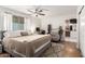 Bright main bedroom featuring a ceiling fan, ensuite bathroom, and adjacent desk area at 6869 E Flossmoor Ave, Mesa, AZ 85208