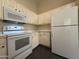Kitchen features white appliances and cabinets and dark tile flooring at 7922 W Alex Ave, Peoria, AZ 85382