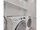 Modern laundry room with front load washer and dryer, white cabinets and shelving at 9630 W Atlantis Way, Tolleson, AZ 85353