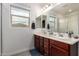 Well-lit bathroom featuring a double sink vanity, and large mirror, with a neighborhood view from the window at 10050 E Texas Ave, Mesa, AZ 85212