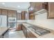 Contemporary kitchen with granite countertops, dark wood cabinetry, and stainless steel appliances including a gas cooktop at 10609 E Durant Dr, Mesa, AZ 85212