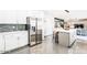 Modern kitchen with stainless steel appliances, white cabinetry, quartz countertops, and an island overlooking the living area at 11215 N 37Th Ave, Phoenix, AZ 85029