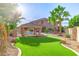 This backyard features a covered patio, swimming pool with waterfall features, and green synthetic grass at 1179 E Regent Dr, Gilbert, AZ 85298
