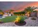 The backyard features manicured landscaping, a built-in grill, palm trees, and green synthetic grass at 1179 E Regent Dr, Gilbert, AZ 85298