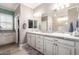 Bright bathroom featuring double sinks, decorative tile countertops, a large mirror, and white cabinets with black hardware at 1179 E Regent Dr, Gilbert, AZ 85298