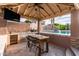 Outdoor kitchen and dining area features a built-in sink and television by a sparkling pool at 1179 E Regent Dr, Gilbert, AZ 85298