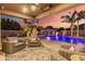 Outdoor patio seating area with a fireplace, outdoor kitchen, bar, and heated pool at 1179 E Regent Dr, Gilbert, AZ 85298