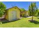 Backyard featuring a yellow storage shed with a well-maintained lawn and landscaping at 1609 E Williams N St, Tempe, AZ 85281