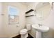 Well-lit half bathroom features a modern vessel sink, floating shelves, and a window for natural light at 16540 W Culver St, Goodyear, AZ 85338
