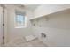 Bright laundry room with tile floors, white walls, a window, and open shelving for storage at 16540 W Culver St, Goodyear, AZ 85338