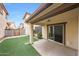 Covered patio with ceiling fan overlooking a well-manicured artificial grass backyard at 16540 W Culver St, Goodyear, AZ 85338