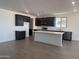 Modern kitchen featuring dark wood cabinetry, a spacious island, stainless steel appliances, and tile flooring at 18418 W Monte Lindo Ln, Surprise, AZ 85387