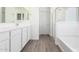 Bright bathroom features a double vanity, tiled floor, and walk in shower with glass doors at 18456 W Monte Lindo Ln, Surprise, AZ 85387