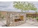 Outdoor stone fireplace with stacked logs, set on a paver patio with a landscaped yard at 18624 W Cathedral Rock Dr, Goodyear, AZ 85338
