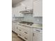 Bright kitchen boasts white cabinets, gray backsplash, and stainless steel range hood at 18624 W Cathedral Rock Dr, Goodyear, AZ 85338