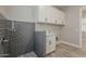 A well-lit laundry room with a dog wash station and white cabinets for optimal storage at 18624 W Cathedral Rock Dr, Goodyear, AZ 85338