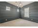 Living room with gray-blue walls, neutral carpet, a modern chandelier and windows with shutters at 18624 W Cathedral Rock Dr, Goodyear, AZ 85338