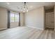 Living room with wood-look laminate flooring, neutral walls, window with patterned curtains, and a modern chandelier at 18624 W Cathedral Rock Dr, Goodyear, AZ 85338