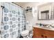 Bathroom with shower, white toilet, wood cabinet and granite countertop, plus wall shelf and decorative shower curtain at 1950 E Dust Devil Dr, San Tan Valley, AZ 85143
