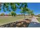 Large green space with mature trees and sidewalk in community park, perfect for outdoor activities at 1950 E Dust Devil Dr, San Tan Valley, AZ 85143