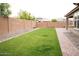 Well-manicured backyard with lush green grass, block wall, and brick-lined walkway at 19814 W Buchanan St, Buckeye, AZ 85326
