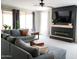 Cozy living room with a large gray sectional sofa, a fireplace with a TV, and bright natural light at 19814 W Buchanan St, Buckeye, AZ 85326