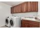 Functional laundry area with front load washer/dryer and upper cabinets at 21472 E Saddle Ct, Queen Creek, AZ 85142