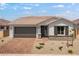 Charming single-story home featuring a brick driveway, two-car garage, and desert landscaping at 25616 N 148Th Dr, Surprise, AZ 85387