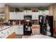 Bright kitchen features white cabinets and black appliances and decorative plants above the upper cabinets at 26145 W Runion Dr, Buckeye, AZ 85396